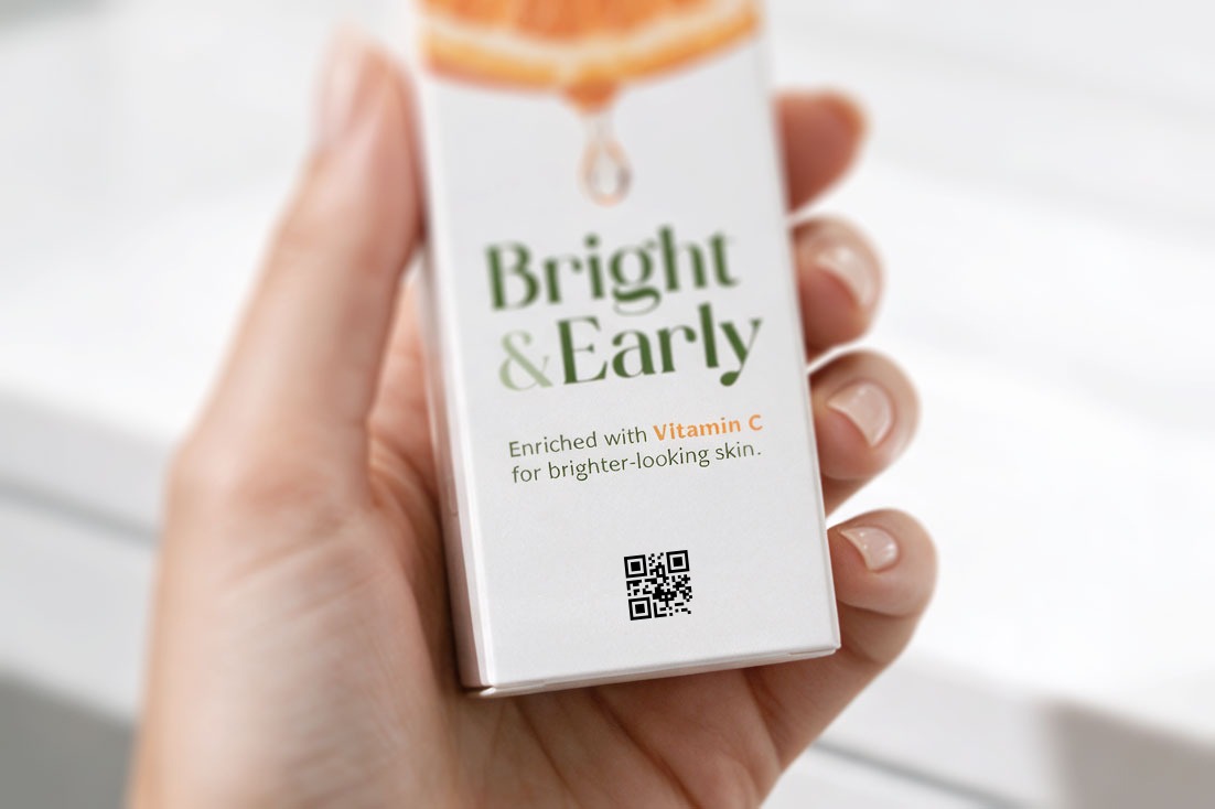 Hand hält eine Pflegeprodukt-Faltschachtel mit 2D-Code